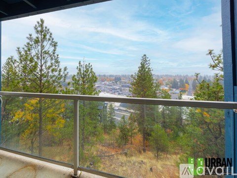 A view from a balcony overlooking a city with trees in the foreground.