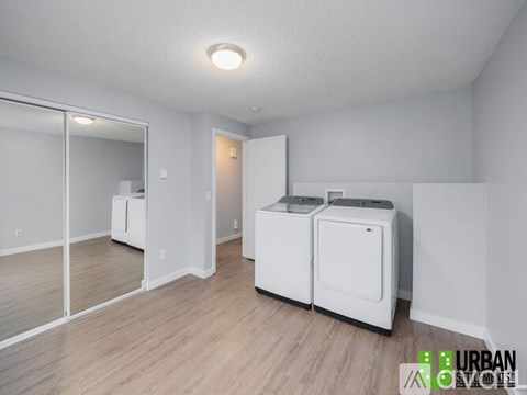 A white room with a wood floor and a wall-mounted dryer.