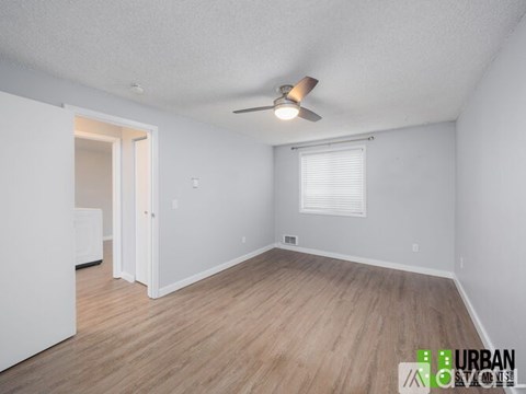 A room with a ceiling fan and wooden flooring.