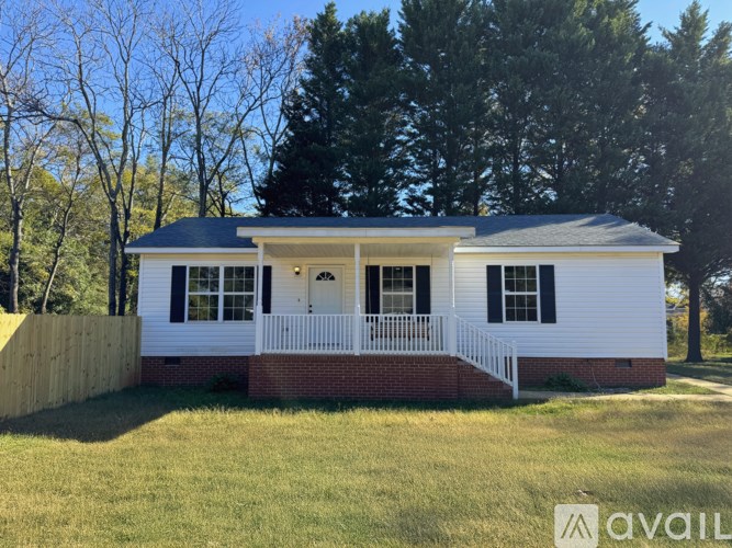 A white house with a black roof and a porch.