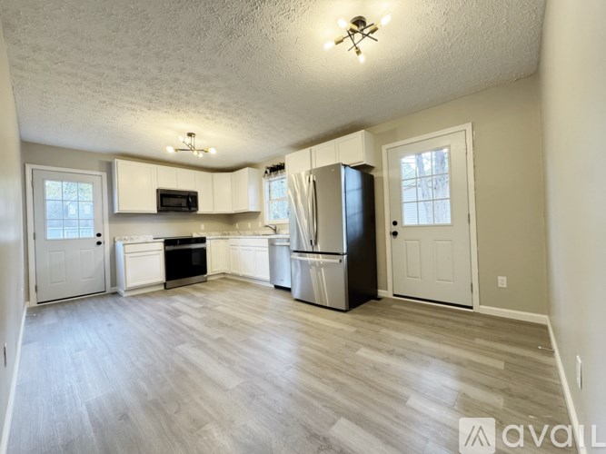 A kitchen with white cabinets and a wooden floor.