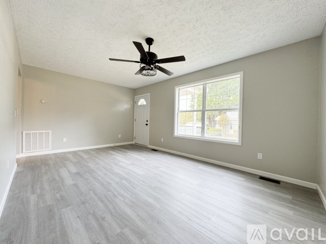 A spacious room with a ceiling fan and a large window.