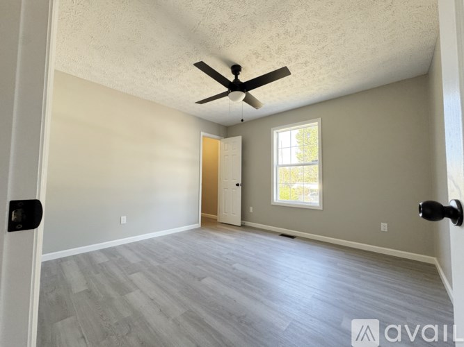 A room with a ceiling fan and a door leading to another room.