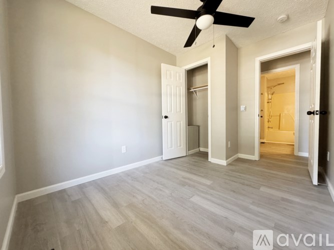 A room with a ceiling fan and light fixture, and a door leading to another room.