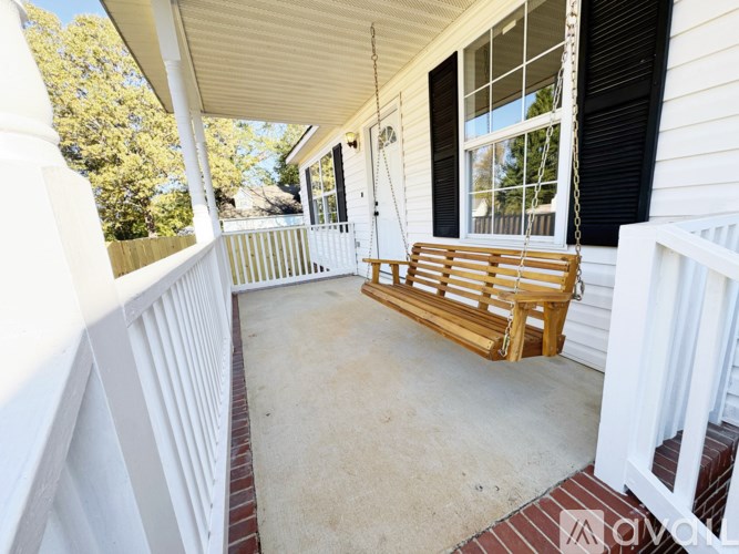 A wooden porch swing sits on a concrete floor.