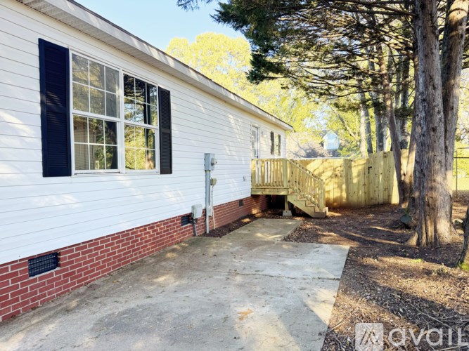 A white house with a black window and a red brick wall.