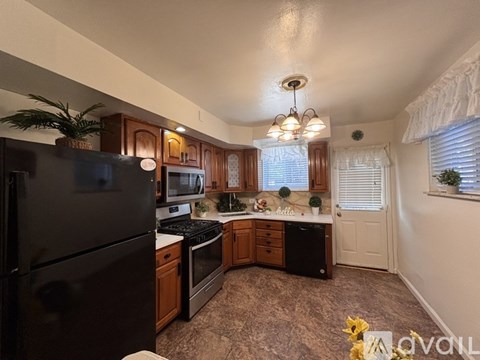 A kitchen with a black refrigerator and wooden cabinets.