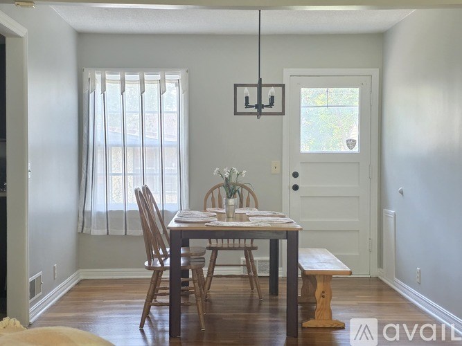 A dining room with a table set for two and a chandelier hanging from the ceiling.