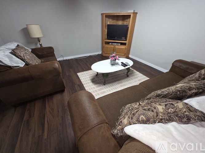 A living room with brown leather couches and a wooden entertainment center.