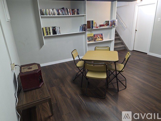 A room with a table, chairs, and a bookshelf.