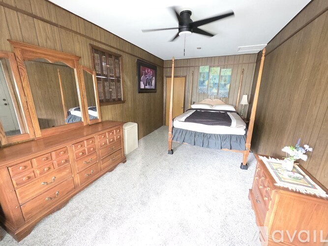 A bedroom with a bed, dresser, and mirror.