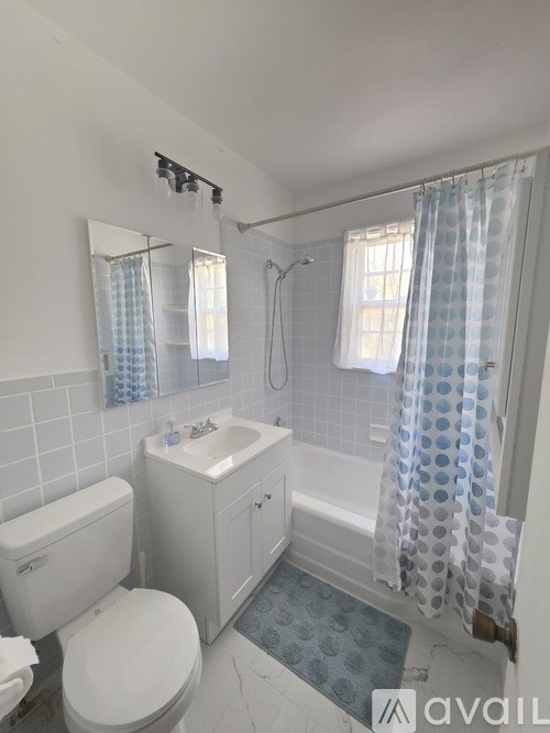 A white bathroom with a toilet, sink, and shower.