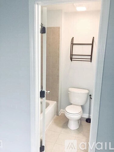 A white toilet in a bathroom with a towel rack on the wall.