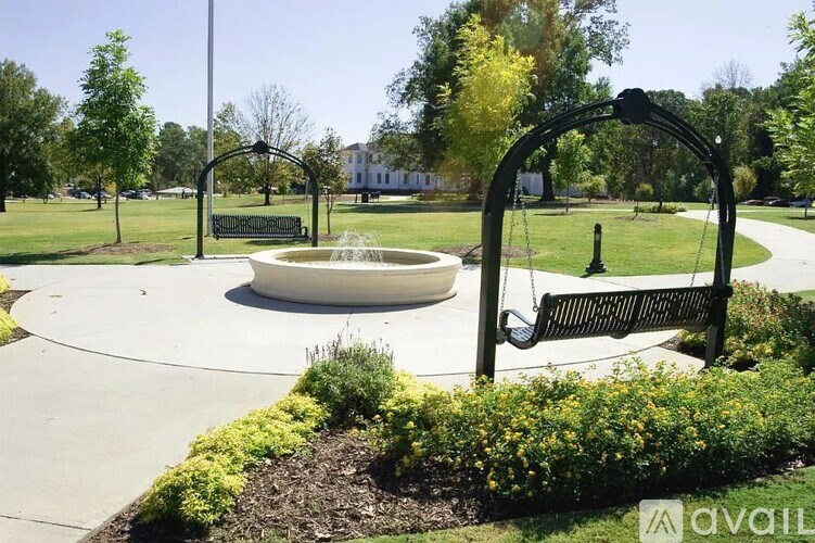 A park with a fountain, bench, and trees.