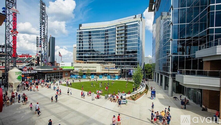 A busy outdoor area with people walking and a large building in the background.