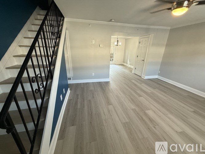 A spacious room with a staircase on the left and a door on the right.