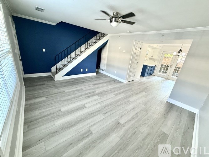 A spacious room with a staircase and a ceiling fan.
