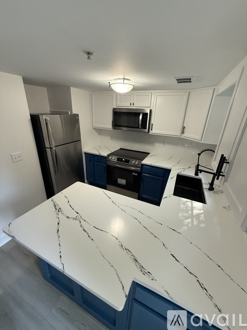 A kitchen with a marble countertop and stainless steel appliances.