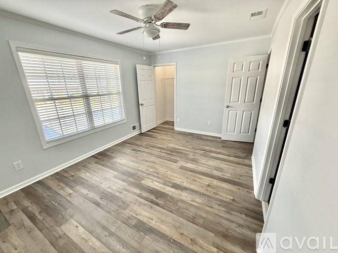A room with a ceiling fan and wooden flooring.