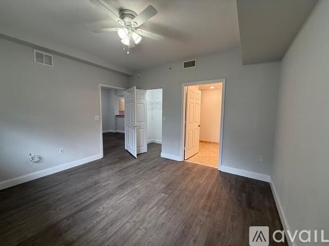 A spacious room with wood flooring and a ceiling fan.