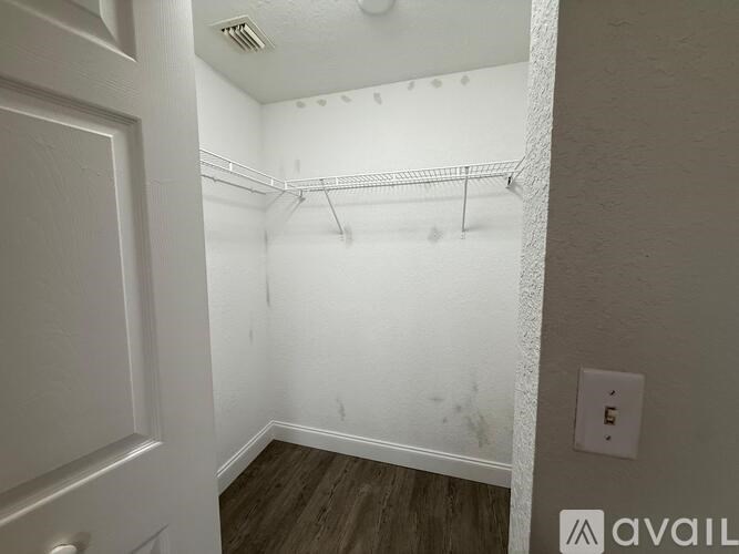 A white closet with a wooden floor and a white door.