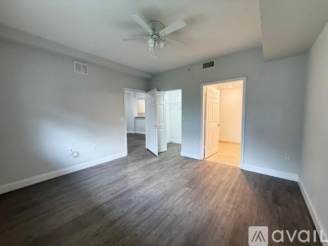 A spacious room with wood flooring and a ceiling fan.