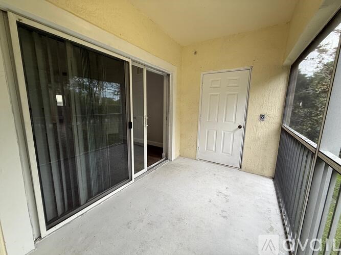 A balcony with a white door and sliding glass doors.