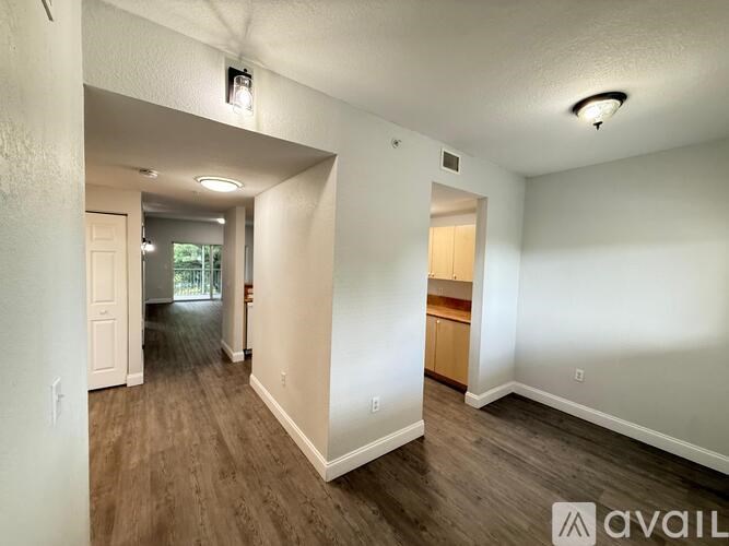 A room with wooden floors and white walls, with a door leading to another room visible in the background.