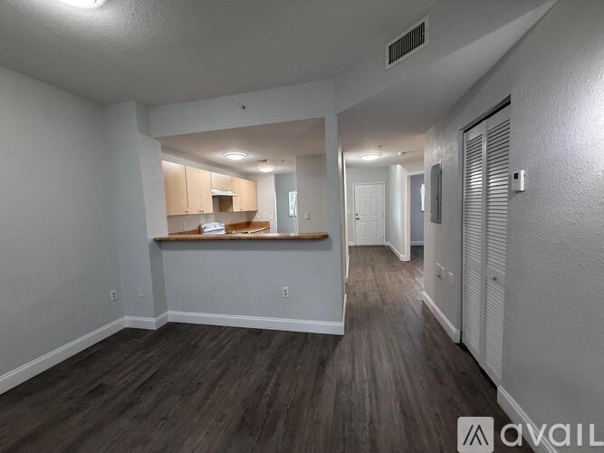 A spacious room with wooden flooring and white walls.