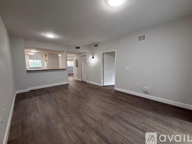 A spacious room with wood flooring and white walls.