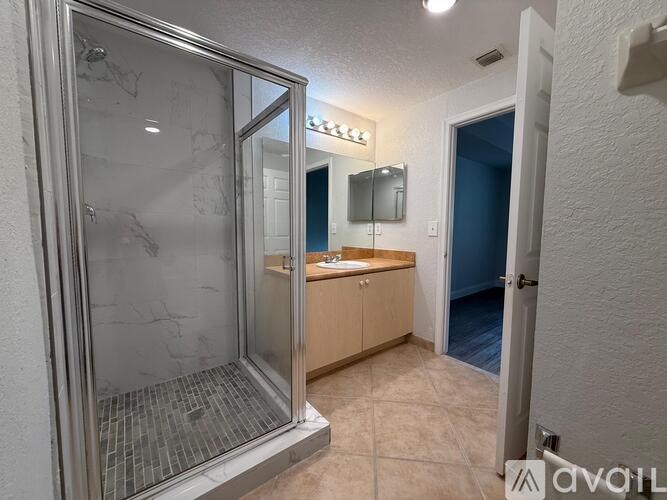 A bathroom with a glass shower door and a mirror above the sink.