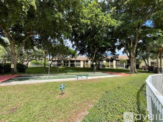 A green sign is in the grass by a walking path.