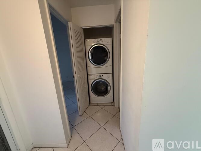 A washing machine is in a small, white-walled laundry room.