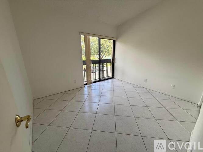 A room with a tiled floor and a door leading to a balcony.