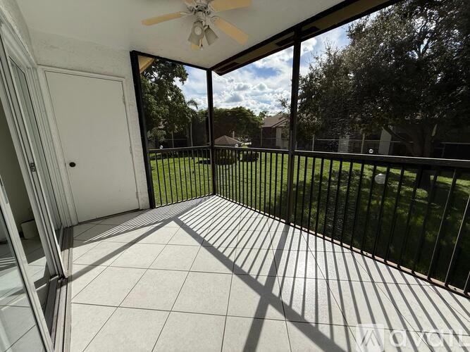 A patio with a ceiling fan and sliding glass doors.