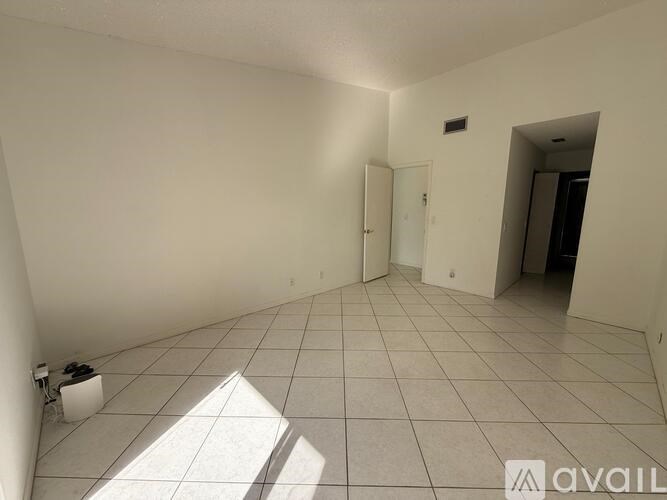 A room with white walls and tiled flooring, with a door on the left and another door on the right.