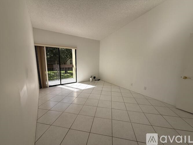A spacious room with a tiled floor and sliding glass doors leading to a balcony.