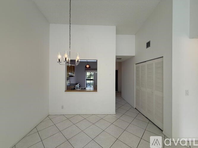 A large empty room with a chandelier and a window.