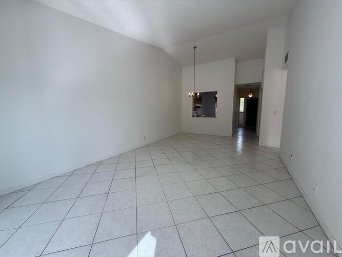 A spacious room with white walls and tiled flooring.