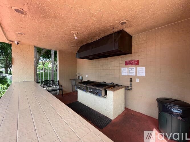 A patio area with a barbecue grill and a trash bin.