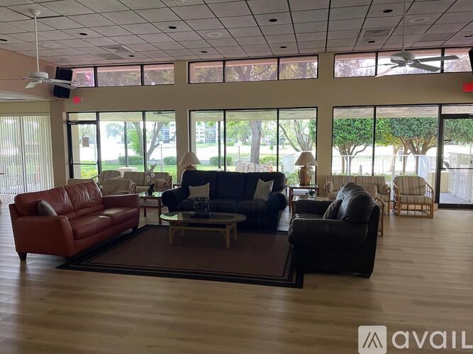 A living room with a red couch, a black couch, and a brown armchair.