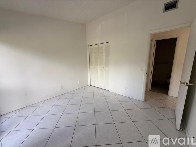 A room with white walls and a tiled floor with a door on the right side.