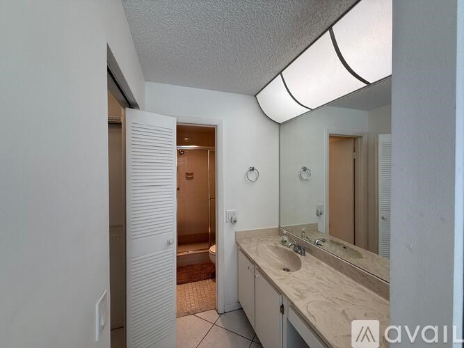 A bathroom with a sink, mirror, and a door.