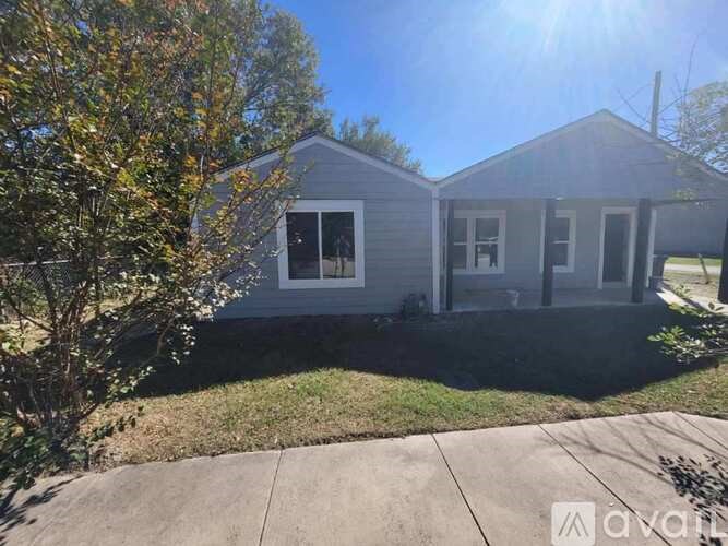 A house with a grey roof and a tree in front of it.