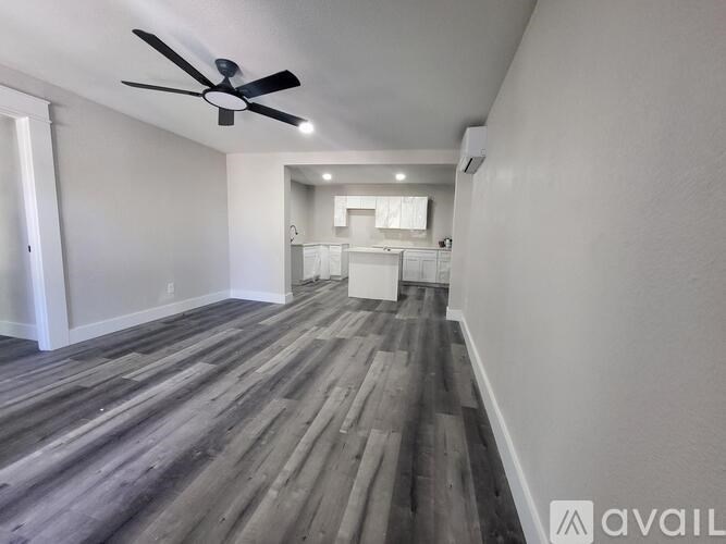 A room with a ceiling fan and wooden flooring.