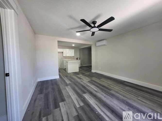 A room with a ceiling fan and wooden flooring.
