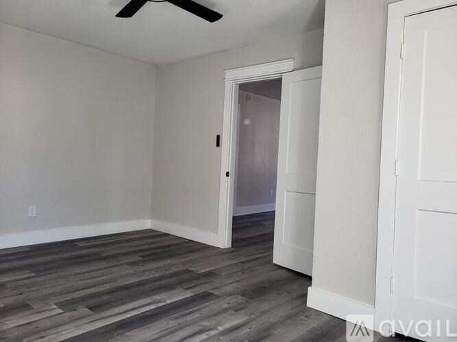 A room with a ceiling fan and a door leading to another room.