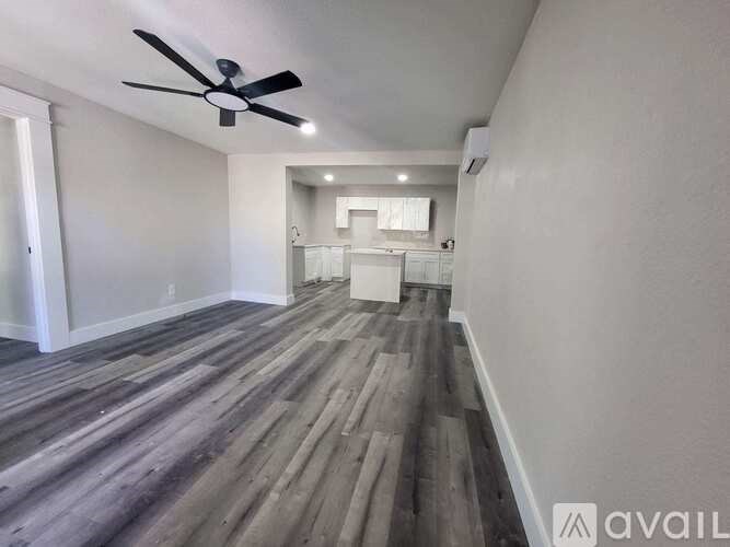 A room with a ceiling fan and wooden flooring.