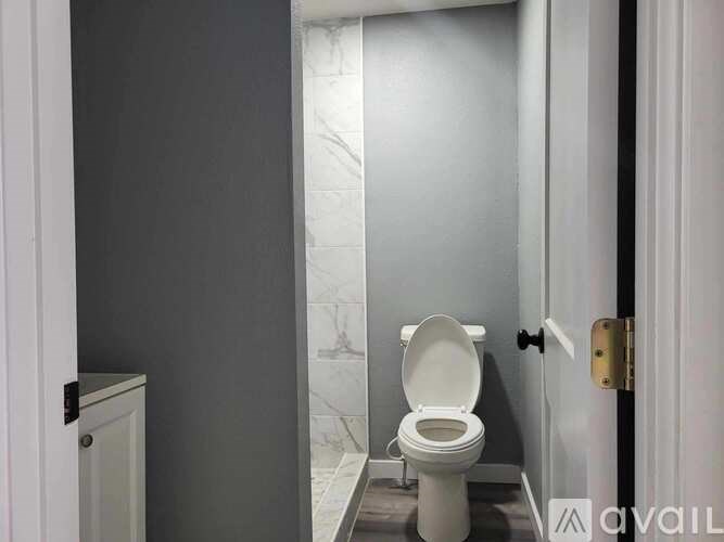 A white toilet in a bathroom with grey walls and a marble floor.