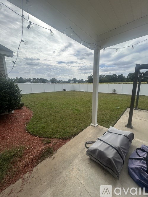 A patio with a white fence and a grey bag on the floor.
